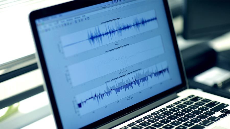 Laptop with signal processing in MATLAB running, showing three time-domain voice signals.