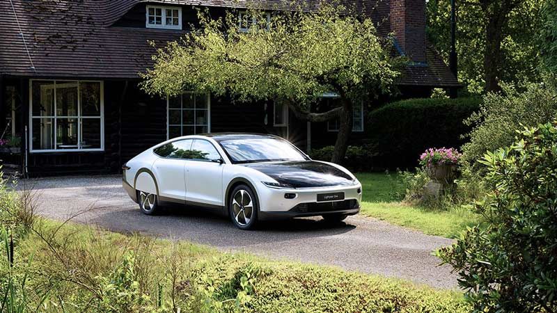 A Lightyear One solar-powered car parked in a driveway in front of a house.